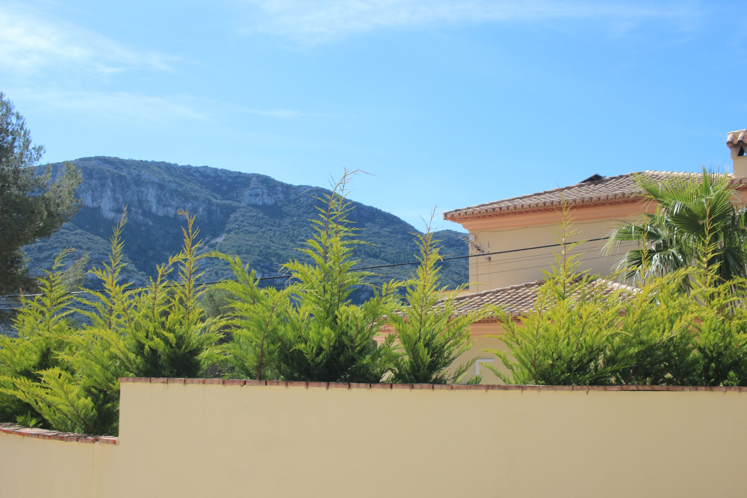 A house in La Drova with a mountain in the background and trees in front