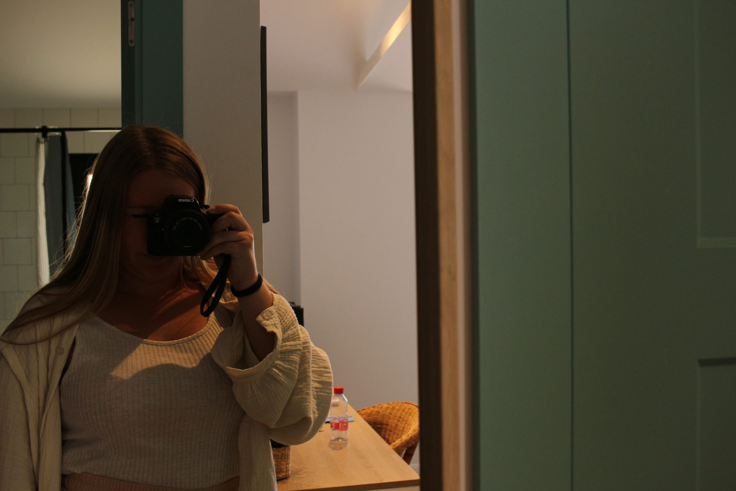 girl standing in front of mirror with camera in hand